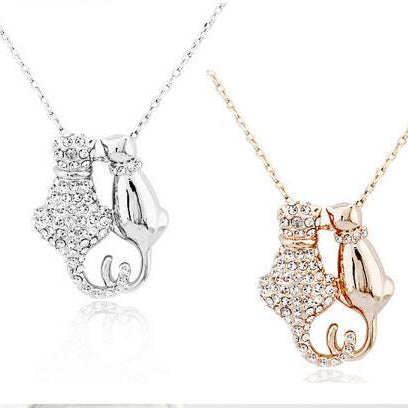 Two cat-shaped pendants, one silver and one rose gold, on white backgrounds.