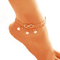 Rose gold anklet with infinity symbol and pearls on a foot against a white background