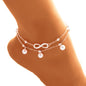 Silver anklet with infinity symbol and pearls on a person's ankle against a white background