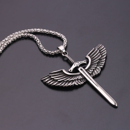 Silver pendant with wings and a sword on a chain against a dark background