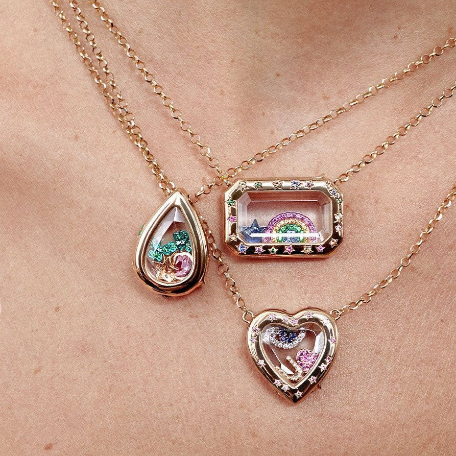 Three necklaces with heart, teardrop, and rectangular pendants on a person's neck.