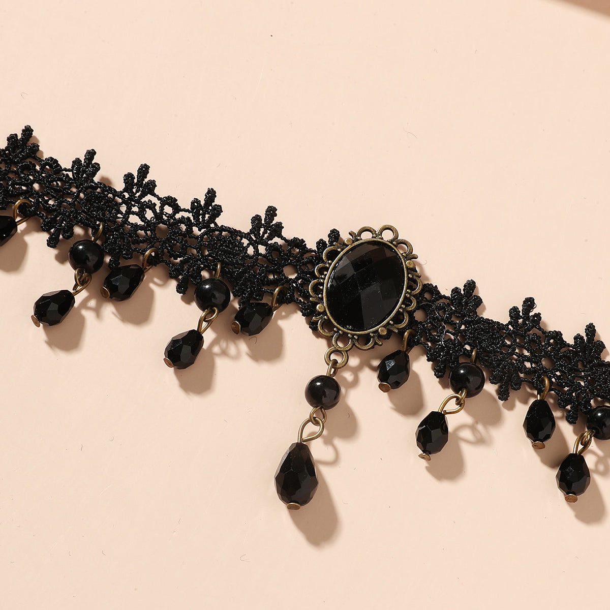 Black lace choker with beads on a beige background