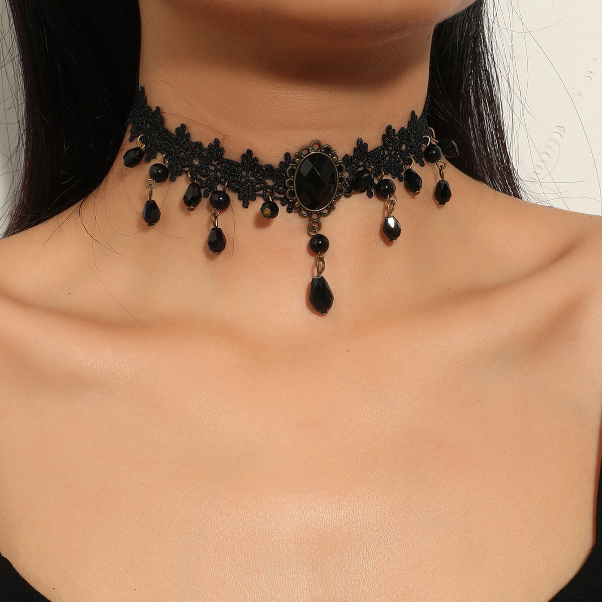 Black lace choker necklace with dangling beads on a model against a neutral background