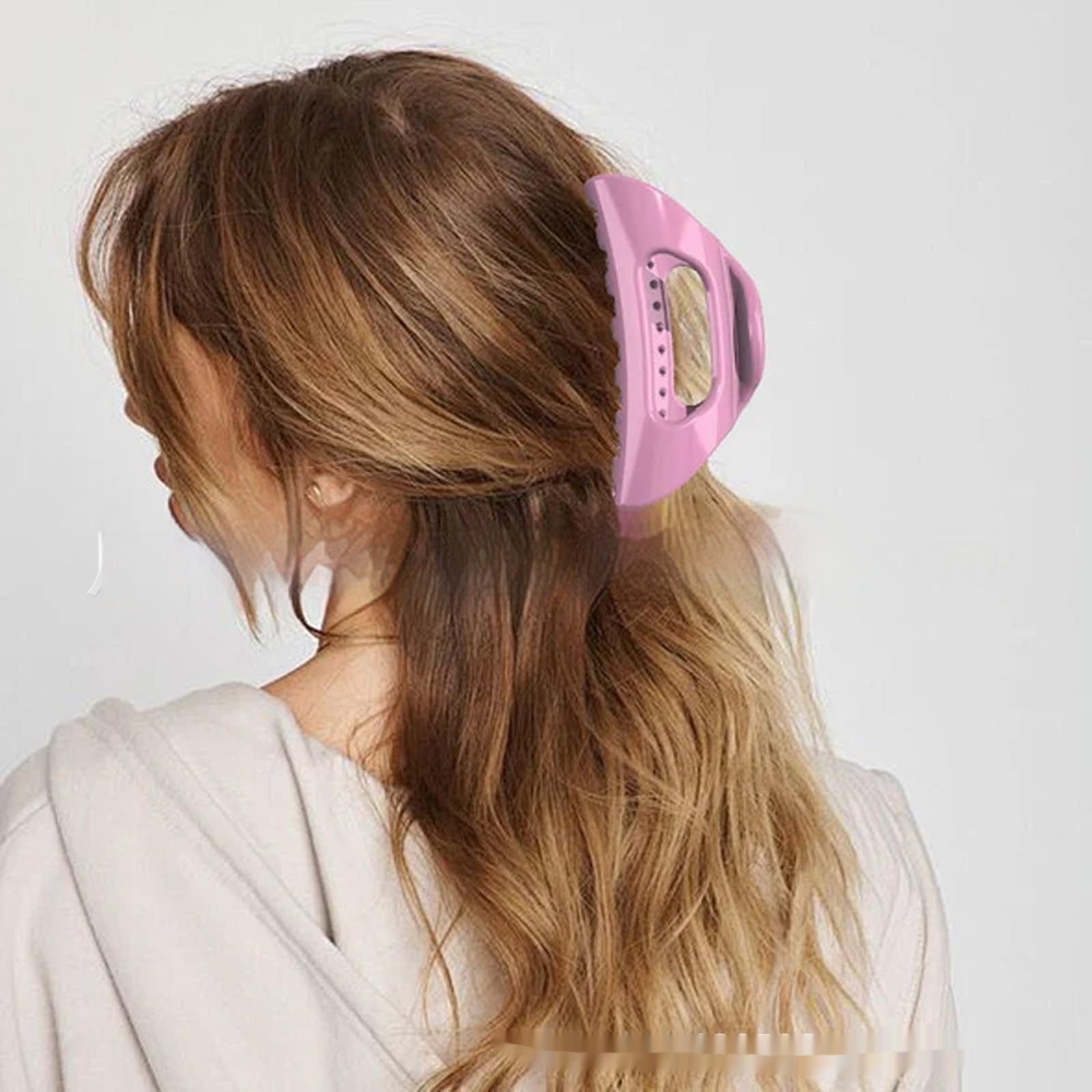 Person with pink hair clip in their hair against a white background