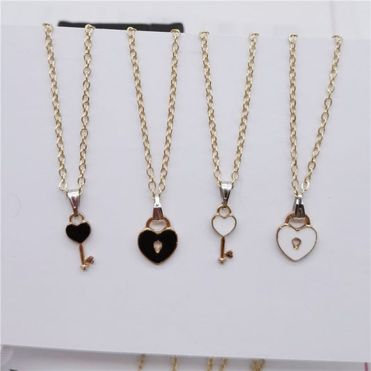 Four gold necklaces with heart and key pendants on a white background