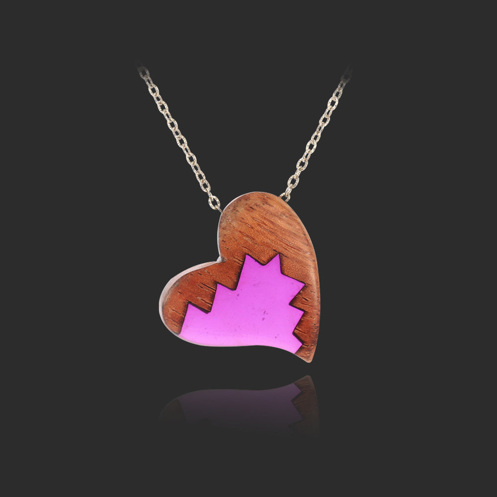 Heart-shaped pendant with pink maple leaf design on a black background