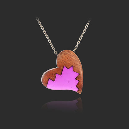 Heart-shaped pendant with pink maple leaf design on a black background
