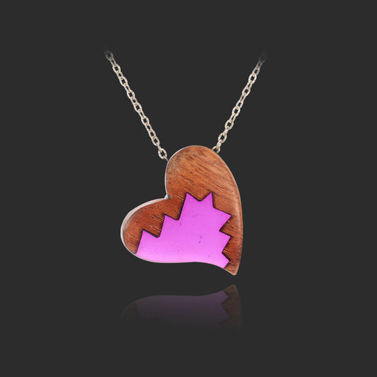 Heart-shaped pendant with pink maple leaf design on a black background
